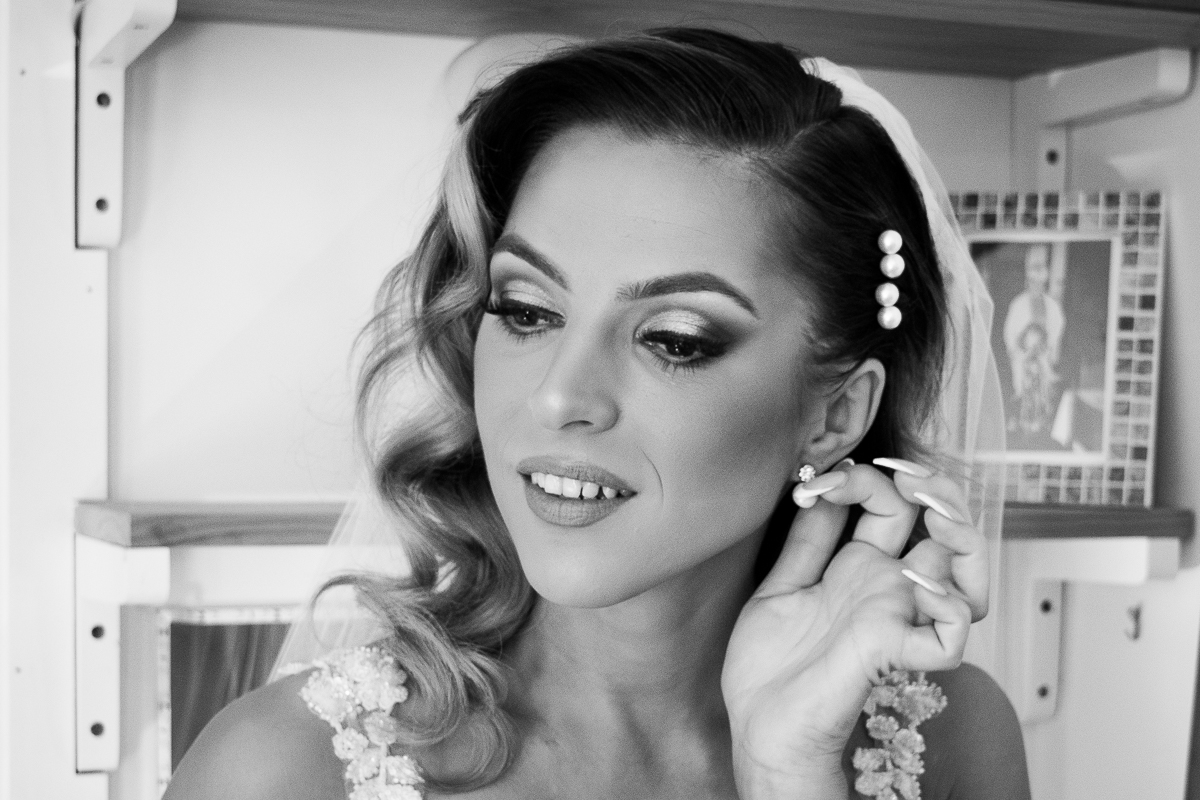 Bride adjusting her pearl earrings in black and white photographed by Olivia Holley Studio