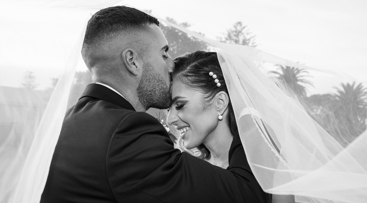 Groom and bride under the bride's veil, Groom kissing his bride's forehead photographed by Olivia Holley Studio