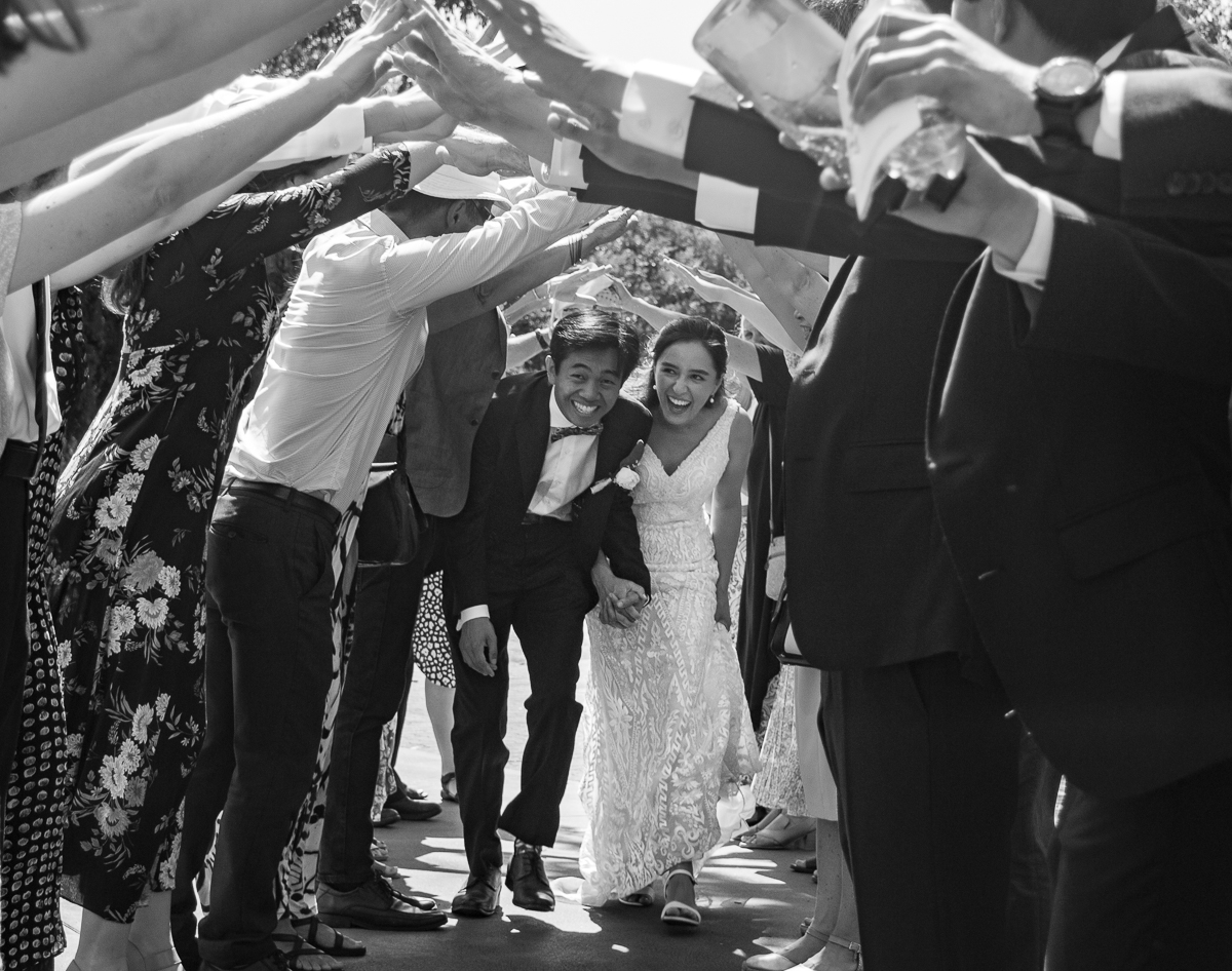 The groom and the bride holding hands and running through the guests archway