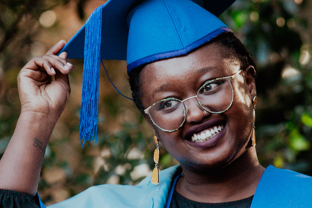 Wollongong graduation session photograph of a graduate smiling and holding cap on campus