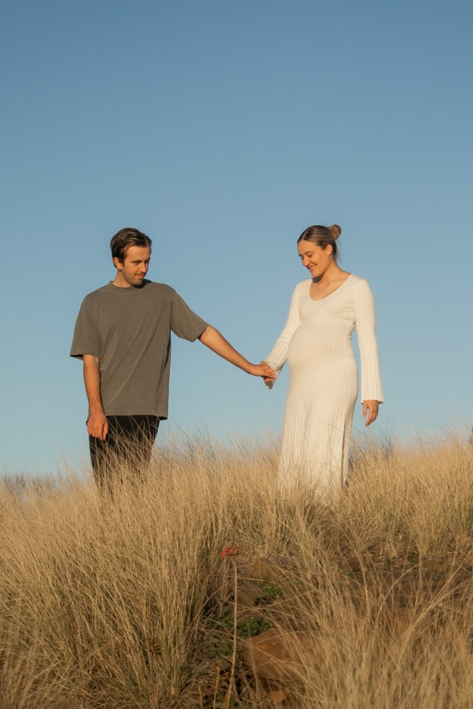 Kiama maternity session of a couple walking together in a field