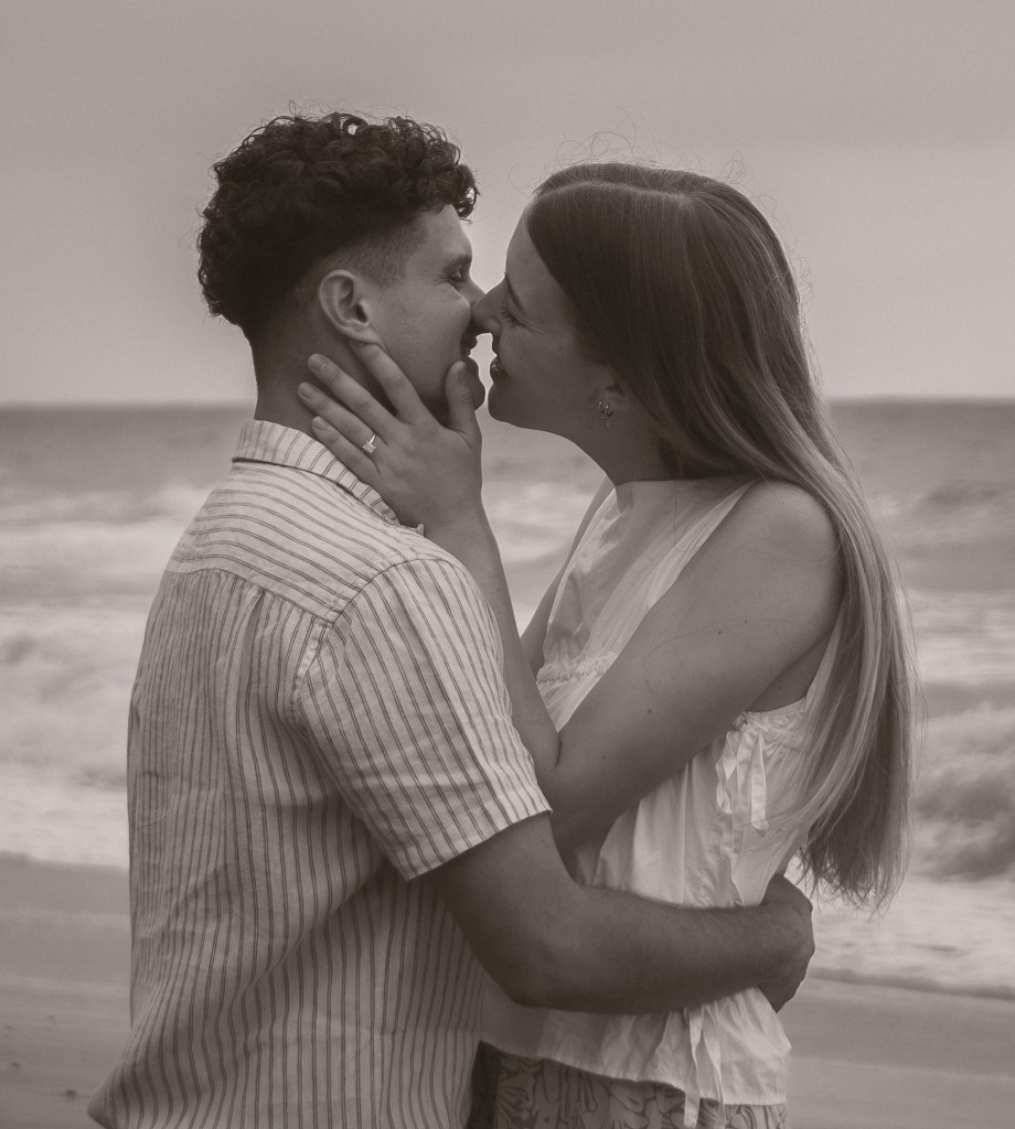 Newly engaged couple about to kiss on the beach black and white photography by Olivia Holley Studio